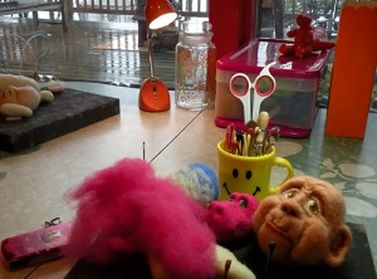 Felt Alive studio worktable with wool roving, color-coded felting needles, and a needle-felted doll head